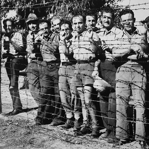Italian-Americans behind metal wire fencing at internment camp