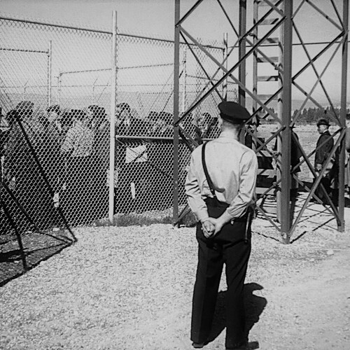 Interned Italians entering internment camp at Fort Missoula in Montana monitored by guard