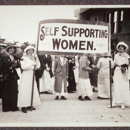 Young women holding a sign which reads, &#039;Self Supporting Women.&#039; Several other women grouped near the banner are holding balls.