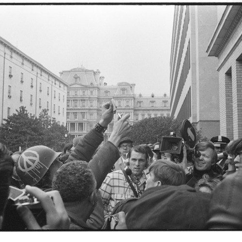 Young man wearing helmet with peace sign, burns his draft card at an anti-draft demonstration at the Selective Service System headquarters