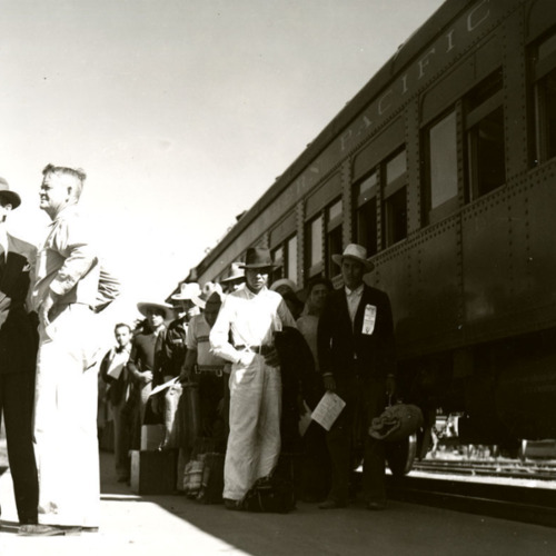 A photo of officials standing with a group of braceros by a Southern Pacific train in California, 1942..png
