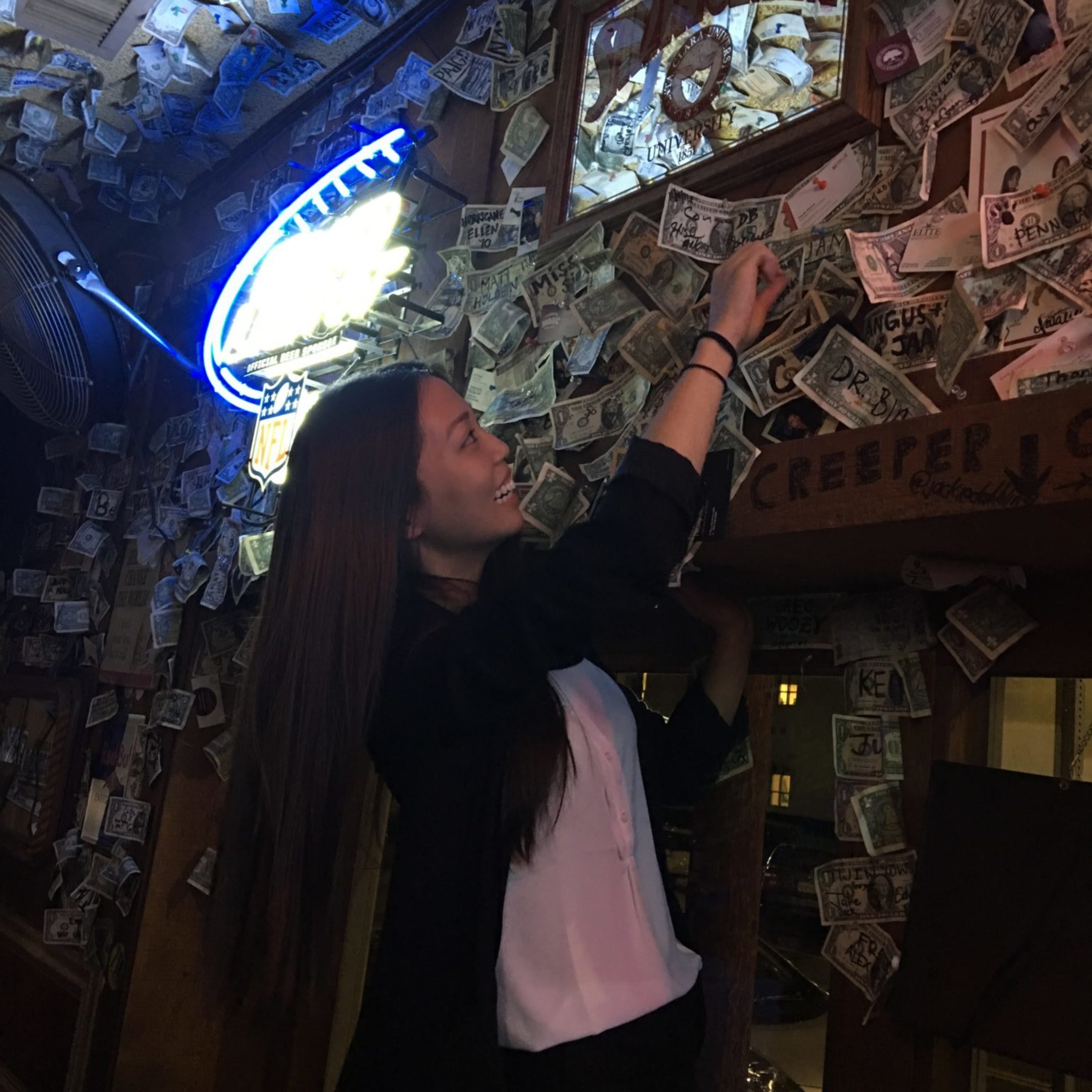 Student pinning dollar to wall of The Hut
