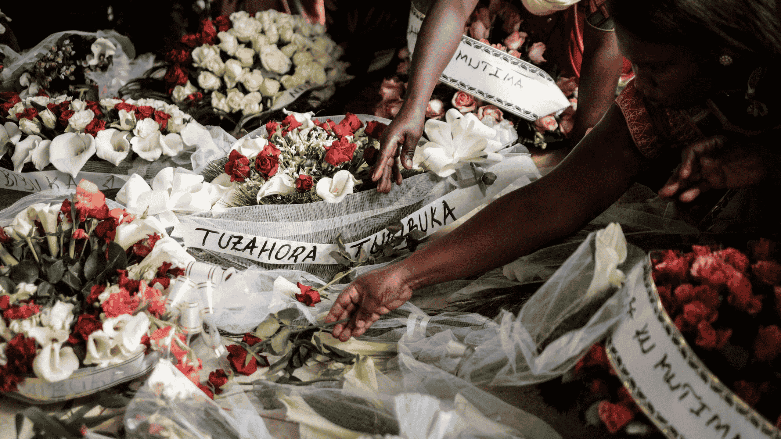 Women carry flowers to offer before the mass funeral to bury 81 coffins containing newly discovered remains of 84,437 victims of the 1994 genocide in the mass grave at the Nyanza Genocide Memorial, suburb of the capital Kigali, on May 4, 2019. - The remains of nearly 85,000 people murdered in Rwanda's genocide were laid to rest on May 4 in a sombre ceremony in Kigali, a quarter of a century after the slaughter.
